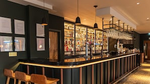 A bar area with stools, a counter, and a display of bottles.