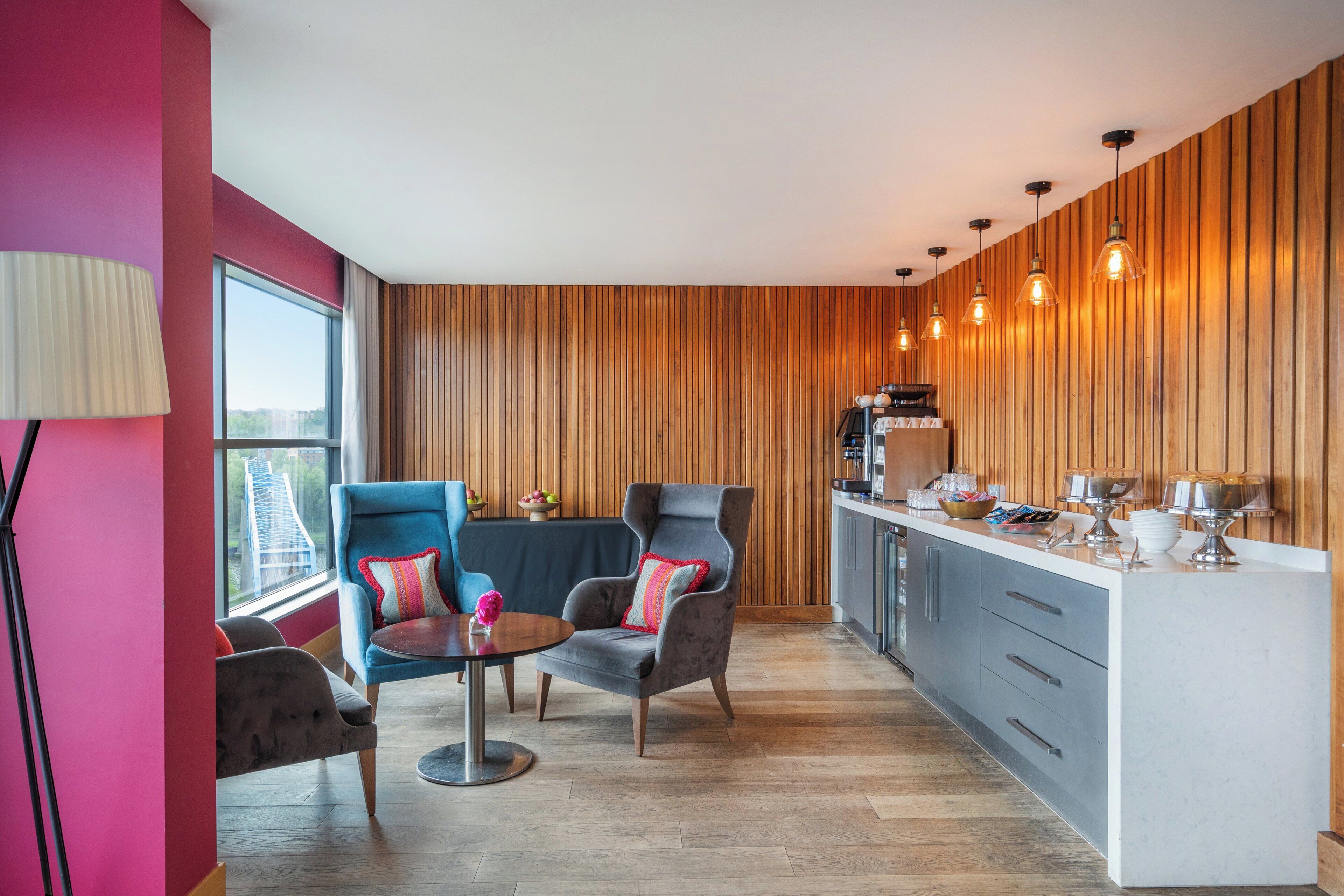 A modern kitchen with wooden paneling, a bar area, and seating with a view of the city.