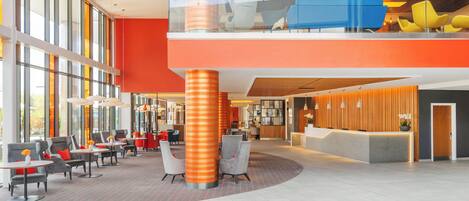 A spacious lobby with a reception desk, seating area, and large windows.