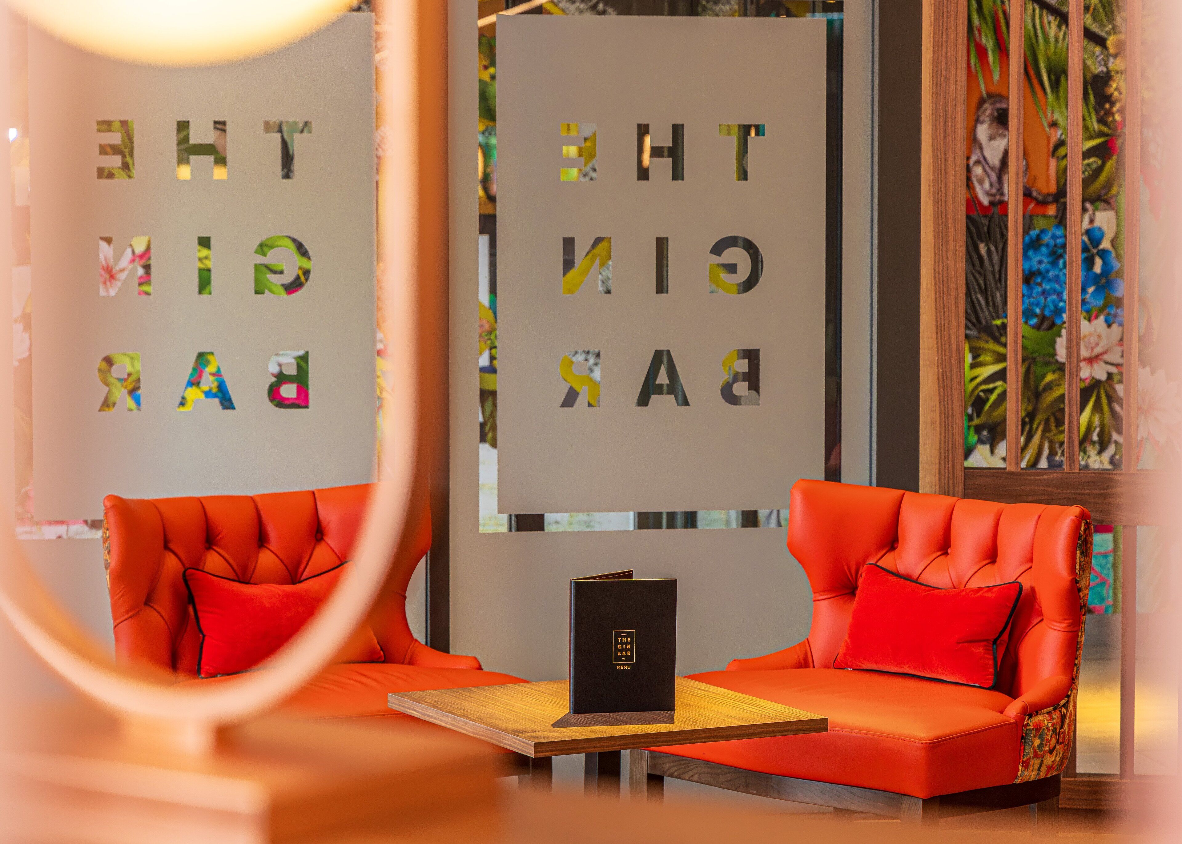 A modern interior with two orange sofas, a wooden table, and a black folder on the table.