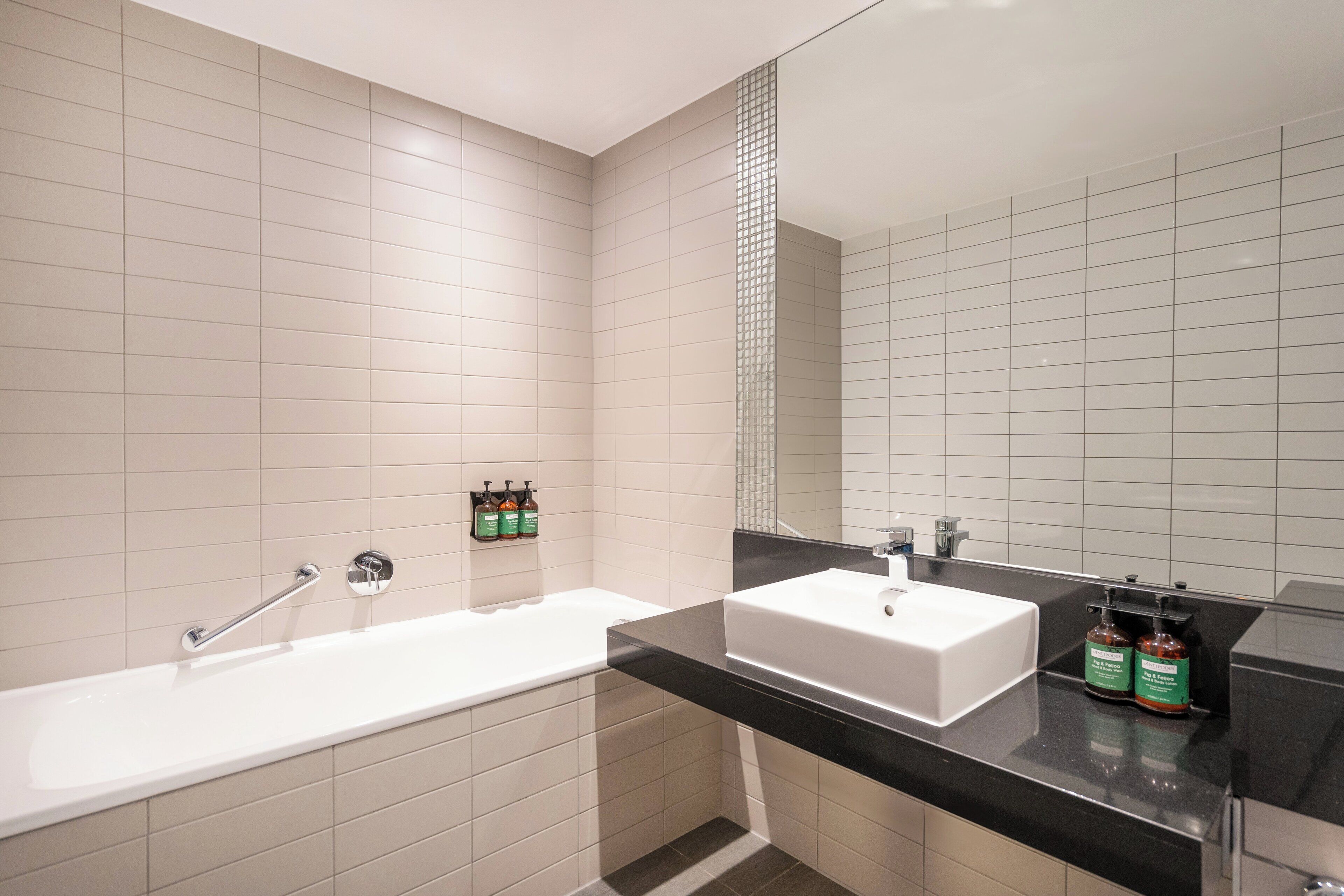 A modern bathroom with a white bathtub, a white sink, and a black countertop.