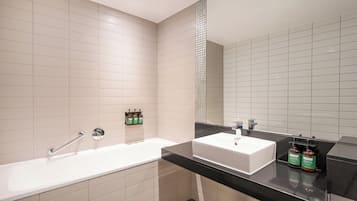 A modern bathroom with a white bathtub, a white sink, and a black countertop.