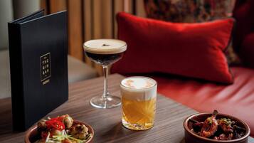 A table with a menu, a martini glass, a beer glass, and a bowl of food.