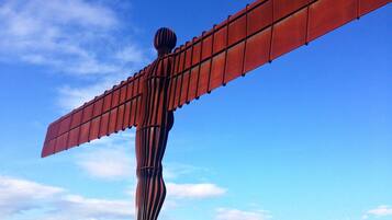 A large outdoor sculpture with a wing-like structure, set against a clear blue sky.