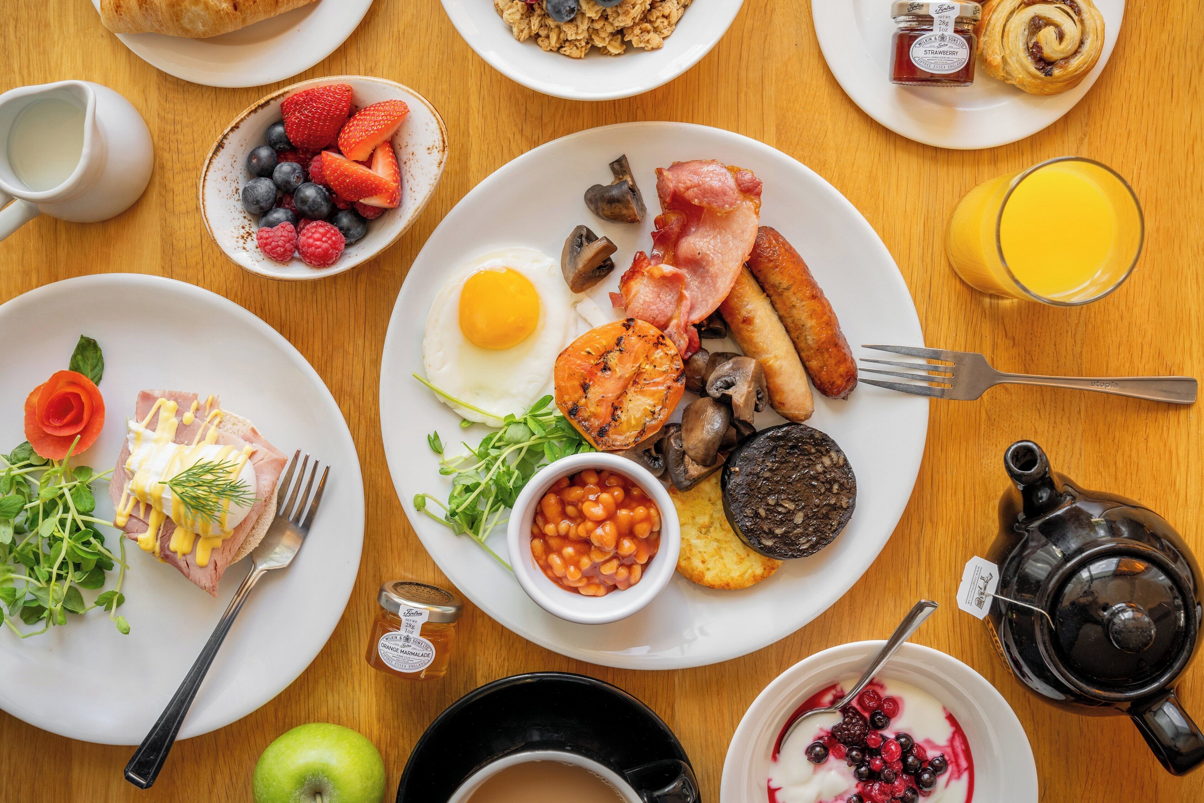 A breakfast table with various dishes including eggs, bacon, mushrooms, and berries.