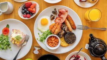A breakfast table with various dishes including eggs, bacon, mushrooms, and berries.