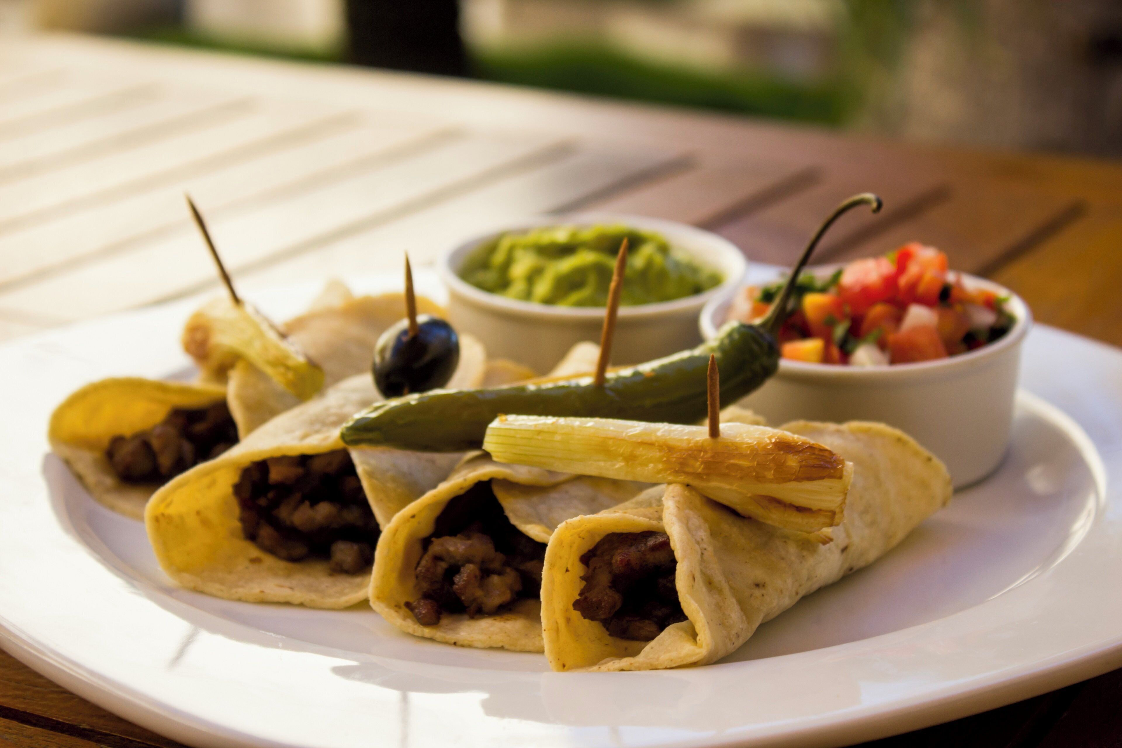Un plato con wraps, un tazón de guacamole y un tazón de salsa.
