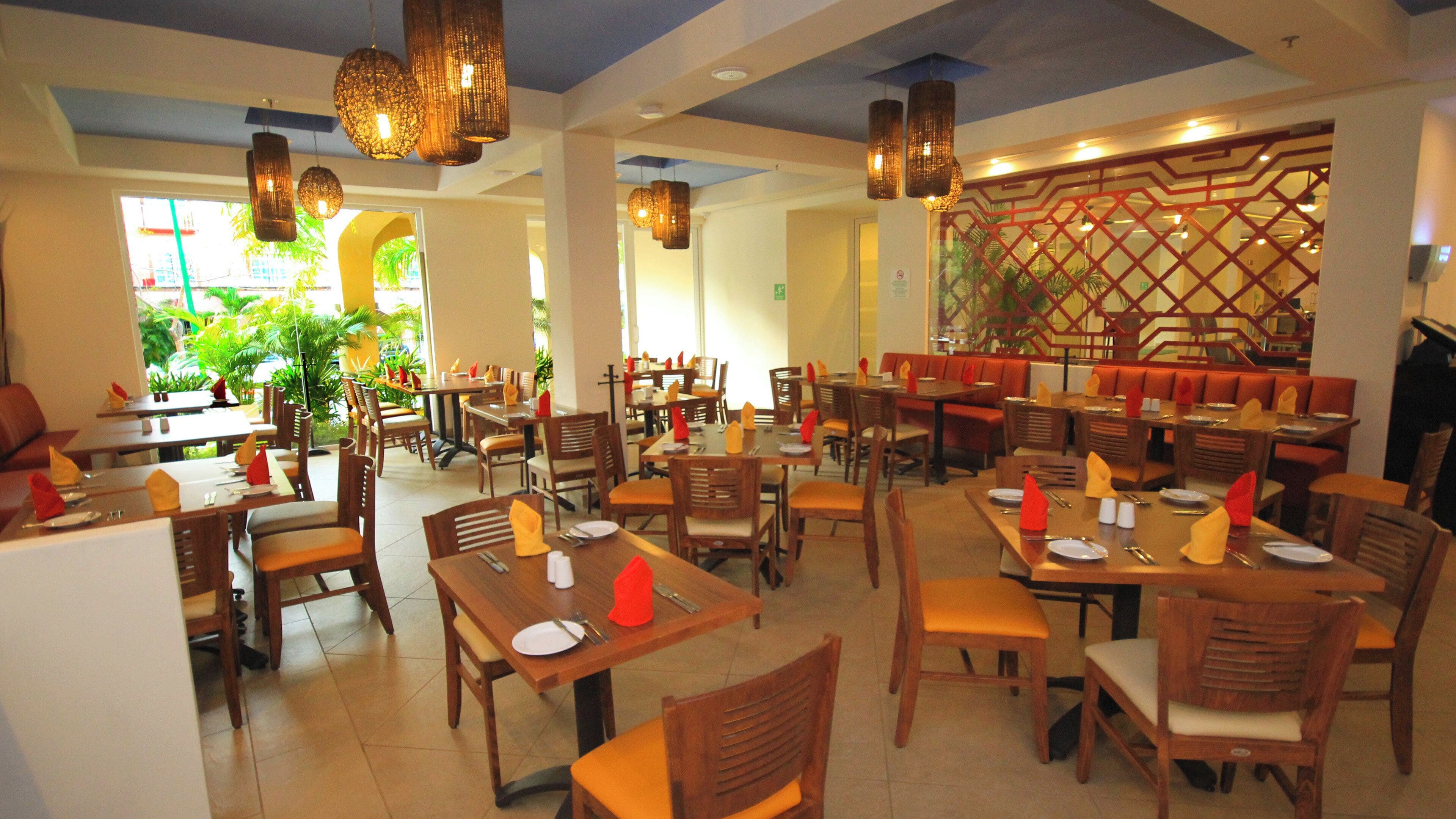 A restaurant with multiple dining tables and chairs, some with red napkins.