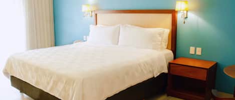 A hotel room with a bed, bedside tables, a chair, and wall-mounted lamps.