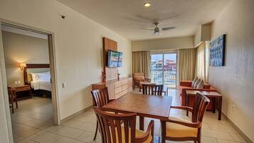 A hotel room with a dining area, a bed, a TV, and a balcony with a city view.