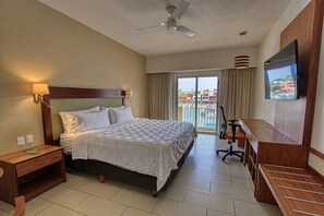 A hotel room with a bed, a desk, a chair, a TV, and a balcony with a view. - Holiday Inn Huatulco by IHG (Santa María Huatulco)