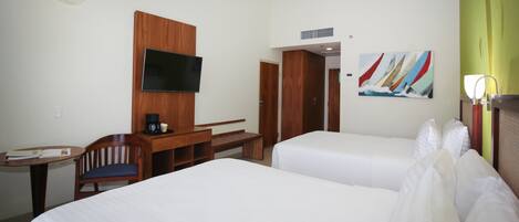 A hotel room with two beds, a desk with a chair, a television, and a painting on the wall.