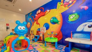 Un espace de jeux pour enfants avec des jouets colorés et une fresque murale.