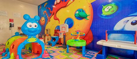 A children's play area with colorful toys and a mural on the wall.