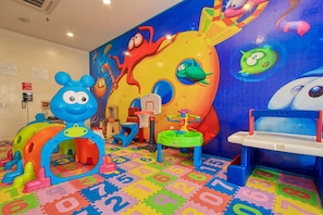 Un espace de jeux pour enfants avec des jouets colorés et une fresque murale.