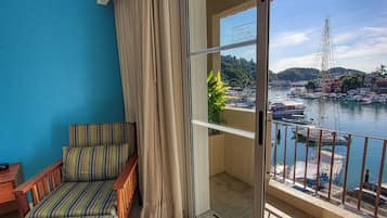 A balcony with a view of a marina, a chair, and a potted plant.