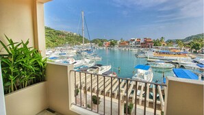 Un balcon avec vue sur une marina, des bateaux et des bâtiments en arrière-plan.