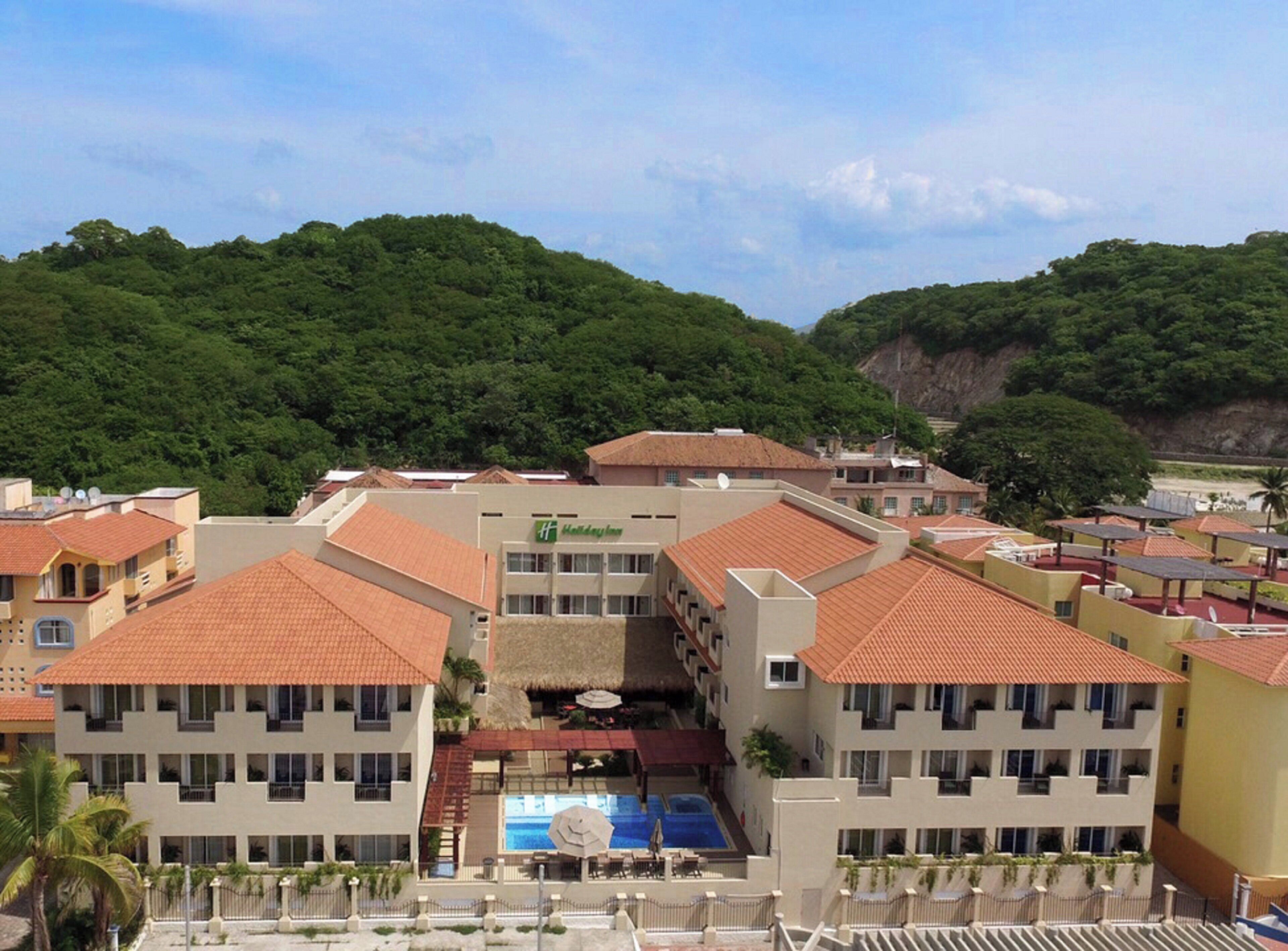 Un hotel con varias construcciones, una piscina y un paisaje montañoso.