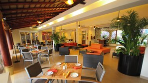 A hotel lobby with seating areas, tables set for dining, and potted plants. - Holiday Inn Huatulco by IHG (Santa María Huatulco)