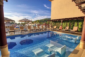 Un espace piscine équipé de chaises longues et de parasols.