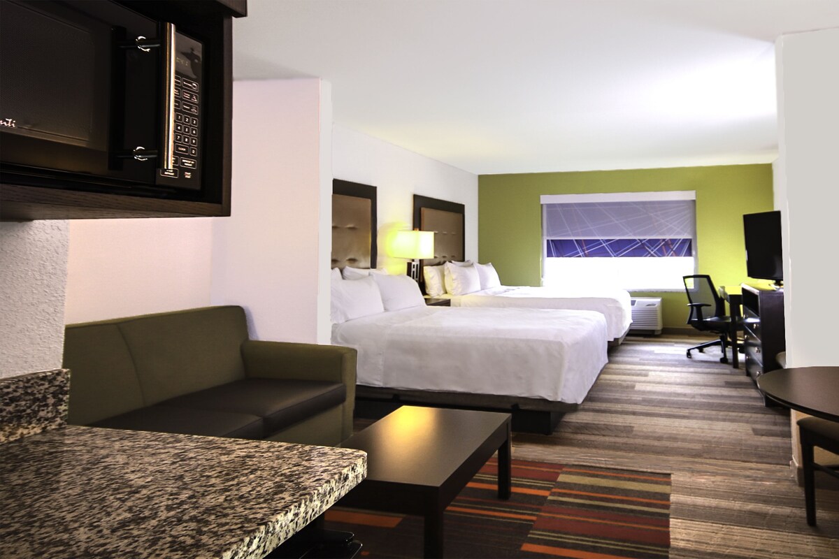 Una habitación de hotel con cama, sofá, escritorio y televisor.