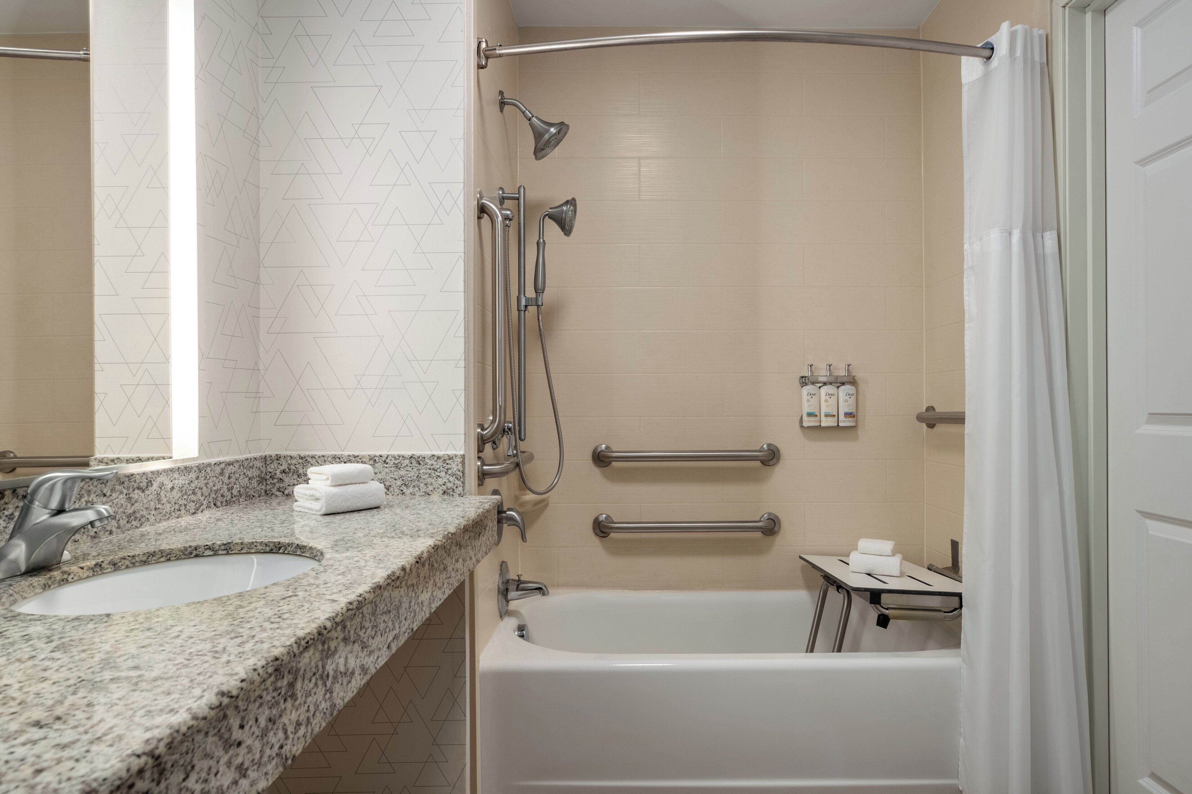 Ein Badezimmer mit einer Granit-Arbeitsplatte, einer Badewanne, einer Dusche inklusive Duschbrause und einem Handtuchhalter.
