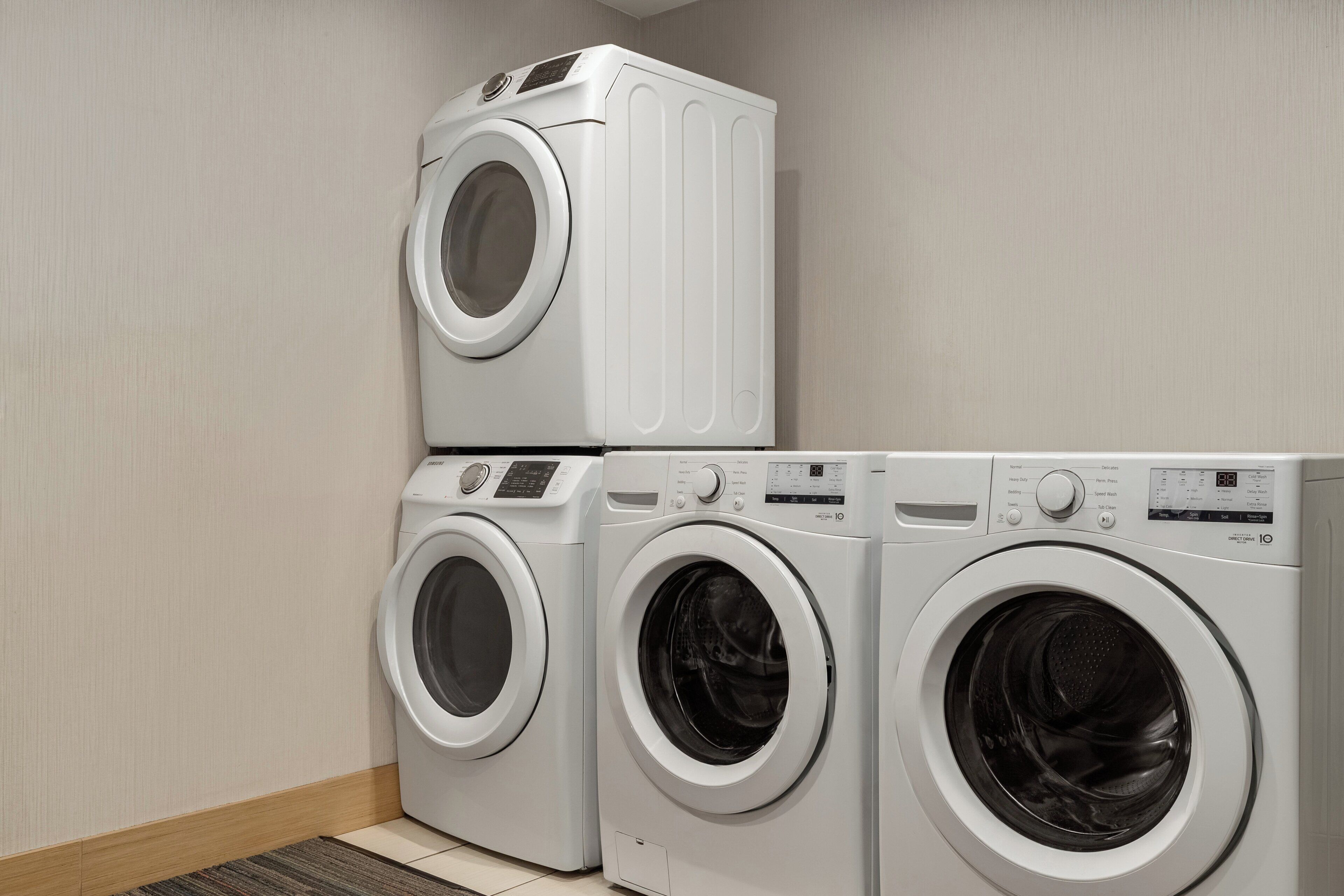 Een wasruimte met drie gestapelde wasmachines.