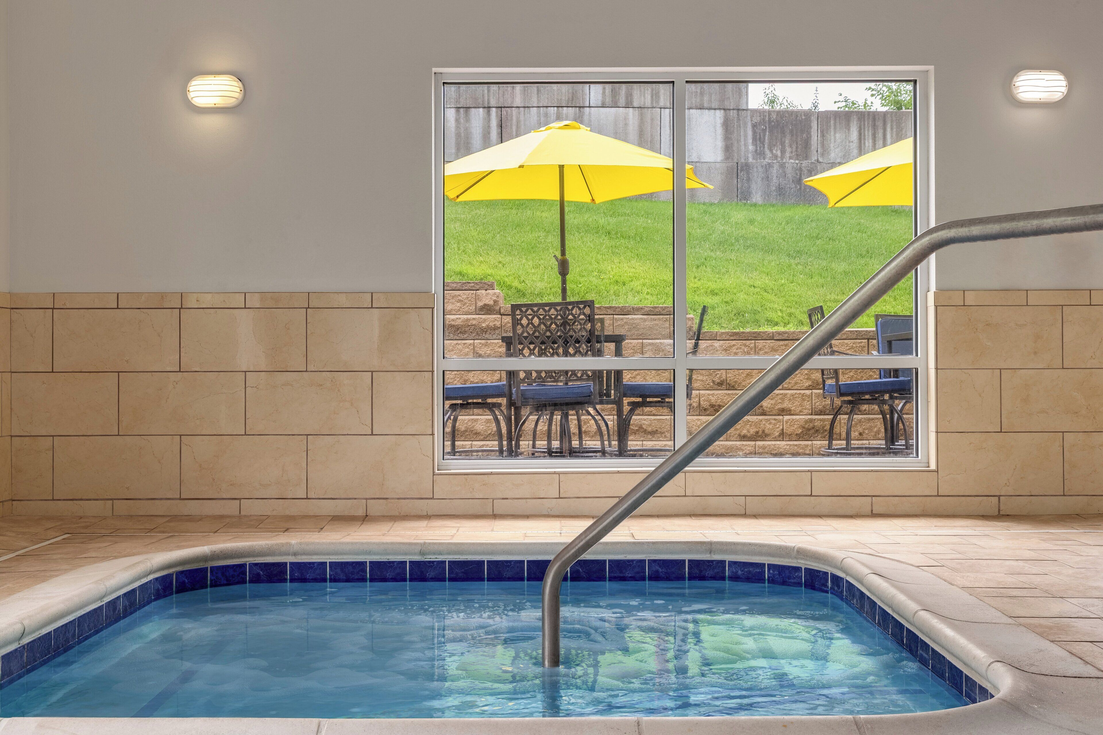 Une piscine donnant sur un patio aménagé avec des chaises et des parasols.