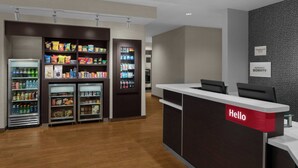 Zona de recepción de un hotel con un letrero que dice 'Hello', mostrador y dispensadores de bebidas refrigeradas.
