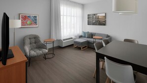 Una sala moderna con sofá, reposapiés y una mesa de comedor.