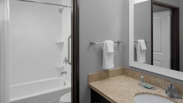 Un baño con bañera, inodoro, lavabo y espejo.