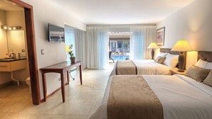 A hotel room with two beds, a desk, a TV, and a view of the pool. - Hotel Tramonto (Jacó)