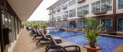 A hotel pool area with lounge chairs and potted plants.