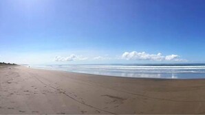 A wide beach with a clear sky and calm sea. - Hotel Tramonto (Jacó)