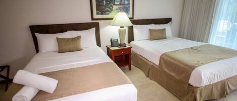 A hotel room with two beds, a nightstand with a lamp, and a painting on the wall.
