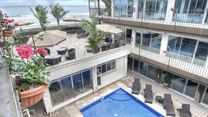 A multi-level outdoor area with a swimming pool, lounge chairs, and potted plants. - Hotel Tramonto (Jacó)