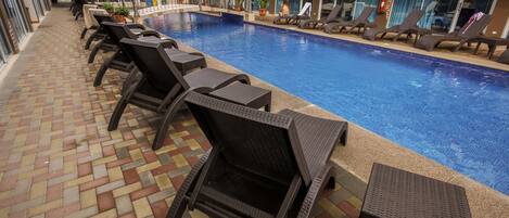 A poolside area with lounge chairs and a tiled walkway.