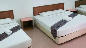 A hotel room with two beds, each with a wooden headboard, a bedside table, and a white bedspread.