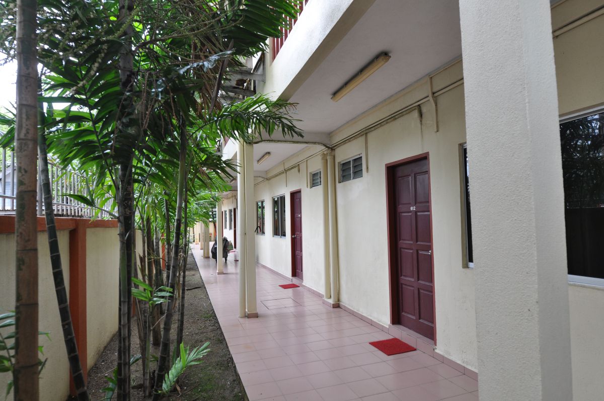 A corridor with a tiled floor, red doors, and a white wall.