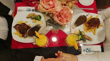 Una mesa de comedor con dos platos de comida, un florero y una vela.