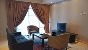 Una sala de estar moderna con un televisor de pantalla plana, dos sofás, un sillón y una mesa de centro.