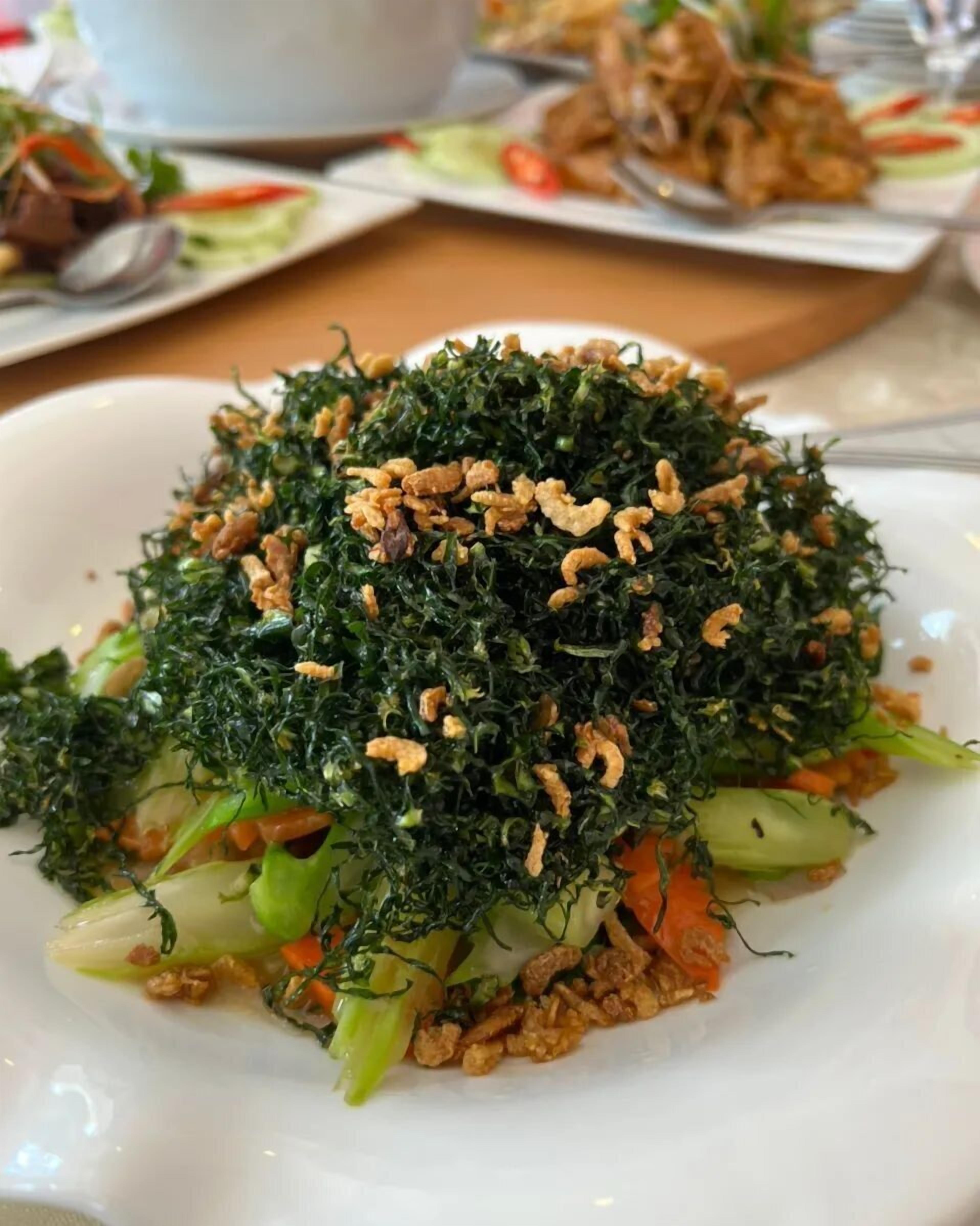 A plate of stir-fried vegetables with crispy fried onions on top.
