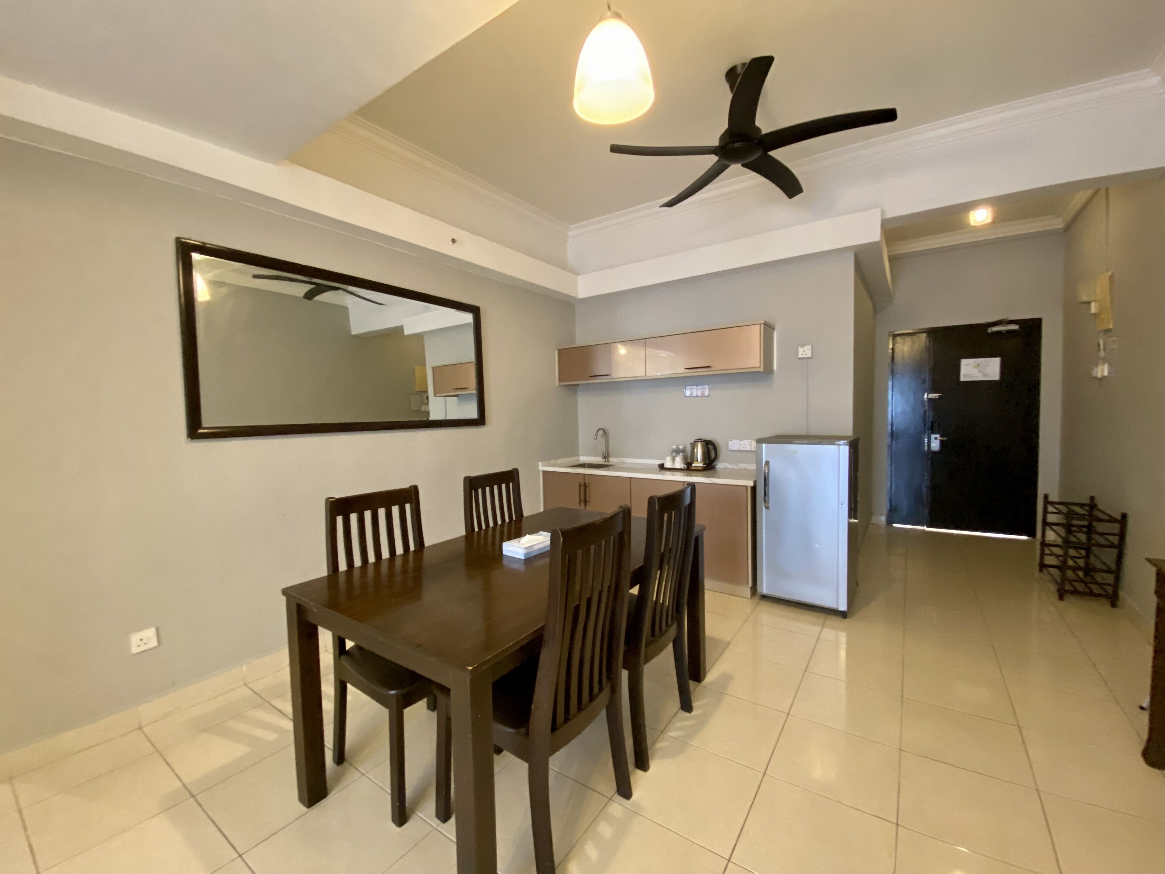 A modern kitchen with a dining area, including a table and chairs, a ceiling fan, and a refrigerator.