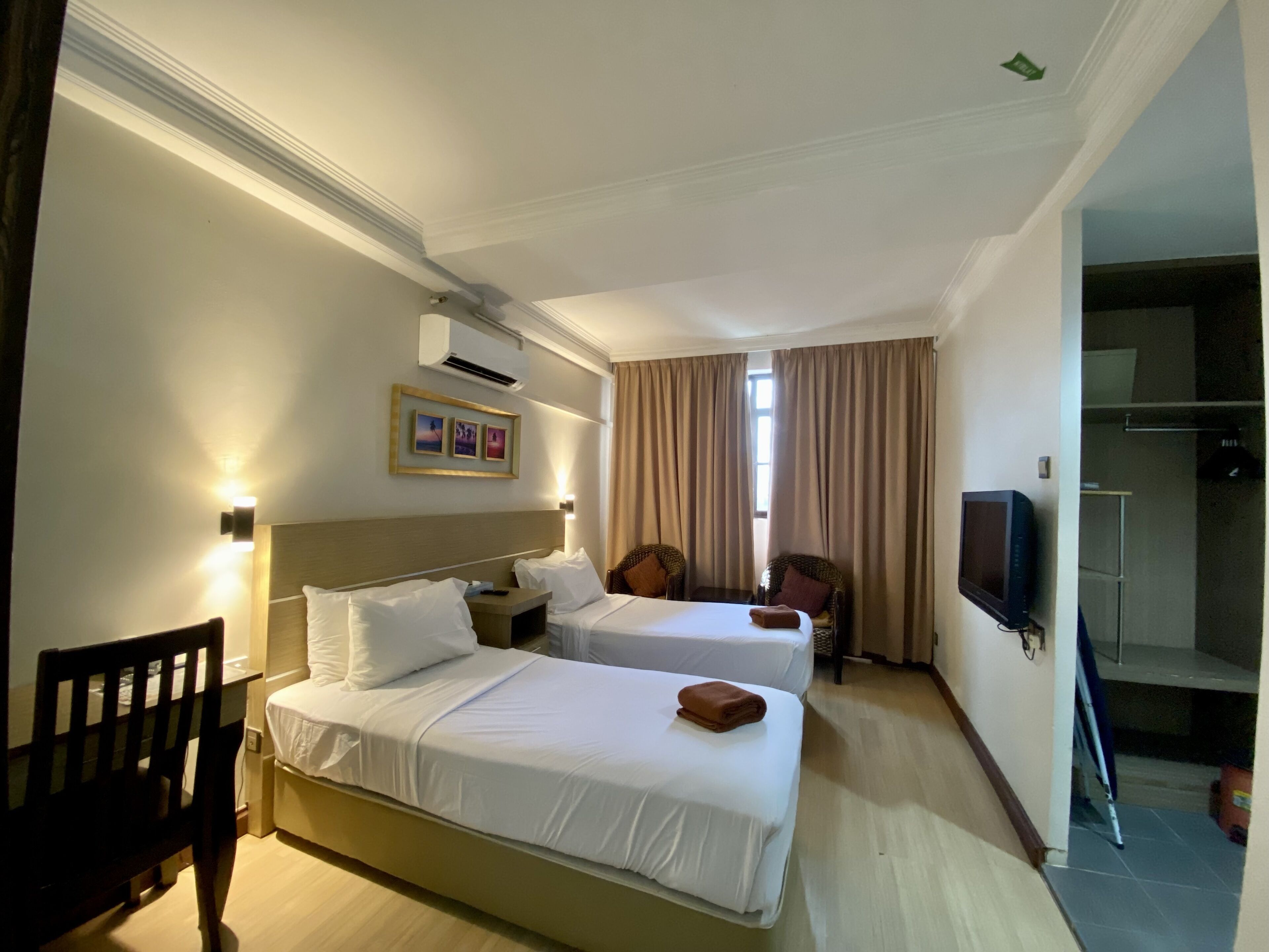A hotel room with two beds, a TV, a chair, and a desk.