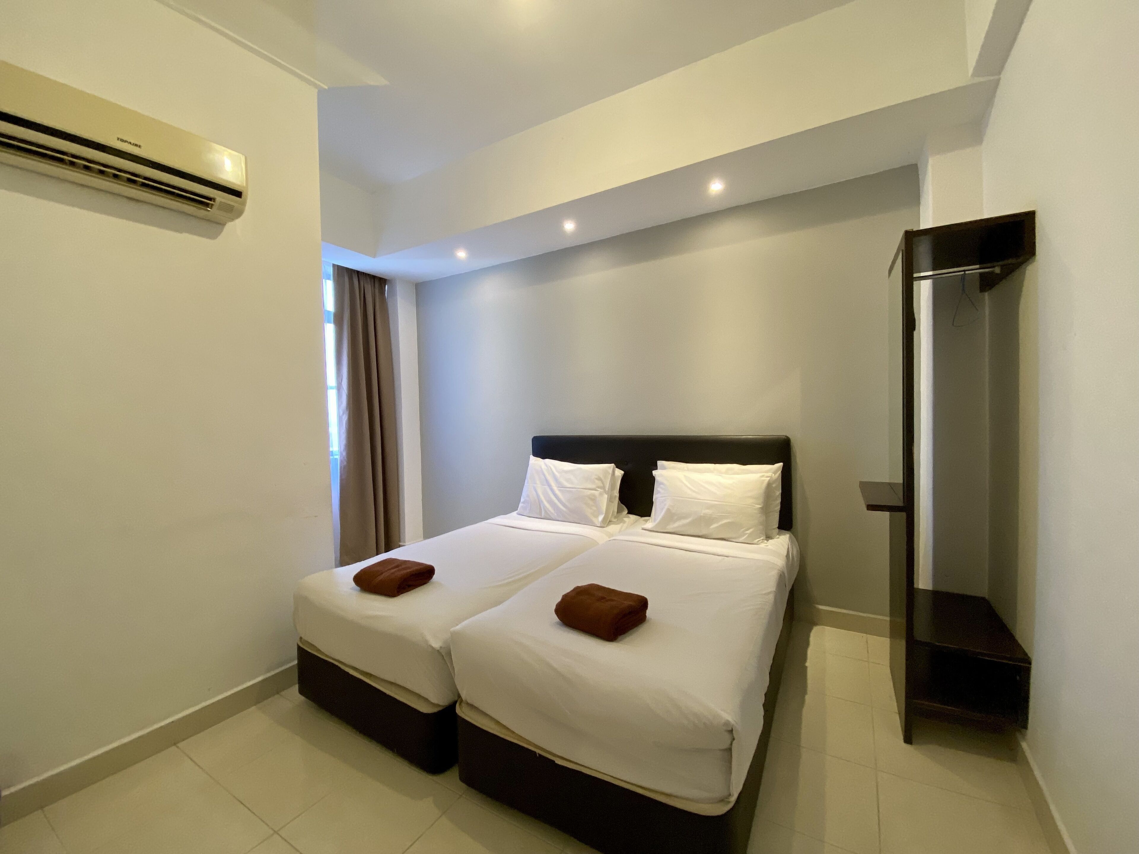 Quarto de hotel com duas camas, um guarda-roupa e um ar condicionado.