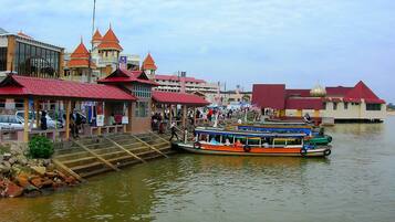 A riverside area with boats, steps leading into the water, and buildings with red roofs.
