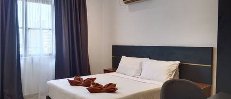 Quarto de hotel com uma cama, uma escrivaninha e ar condicionado.