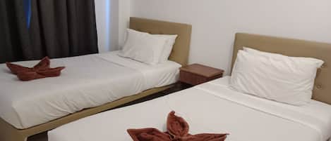 Two twin beds with white linens and brown towels folded on them.