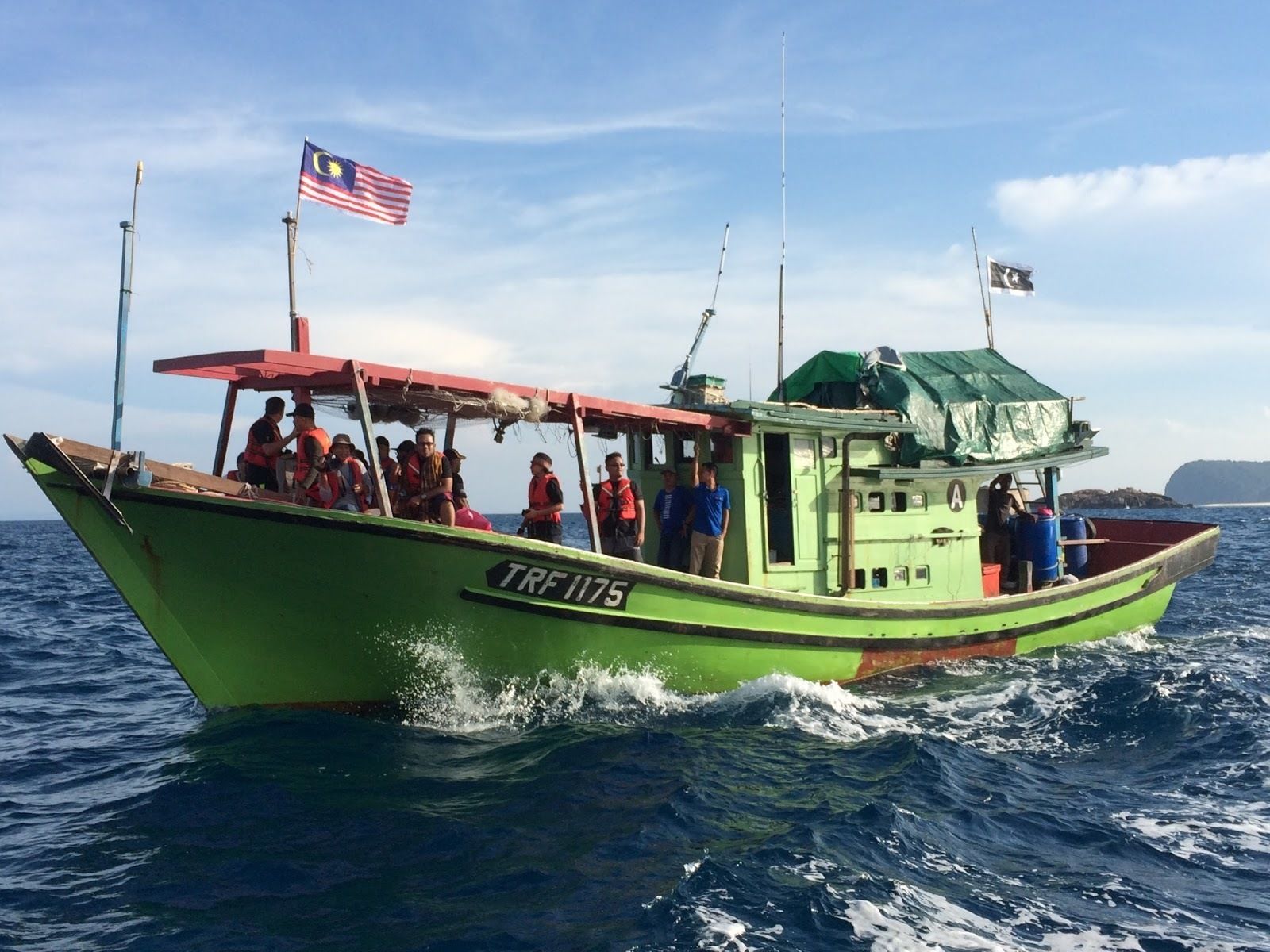 A green boat with the registration number TRF 1175 on the water.