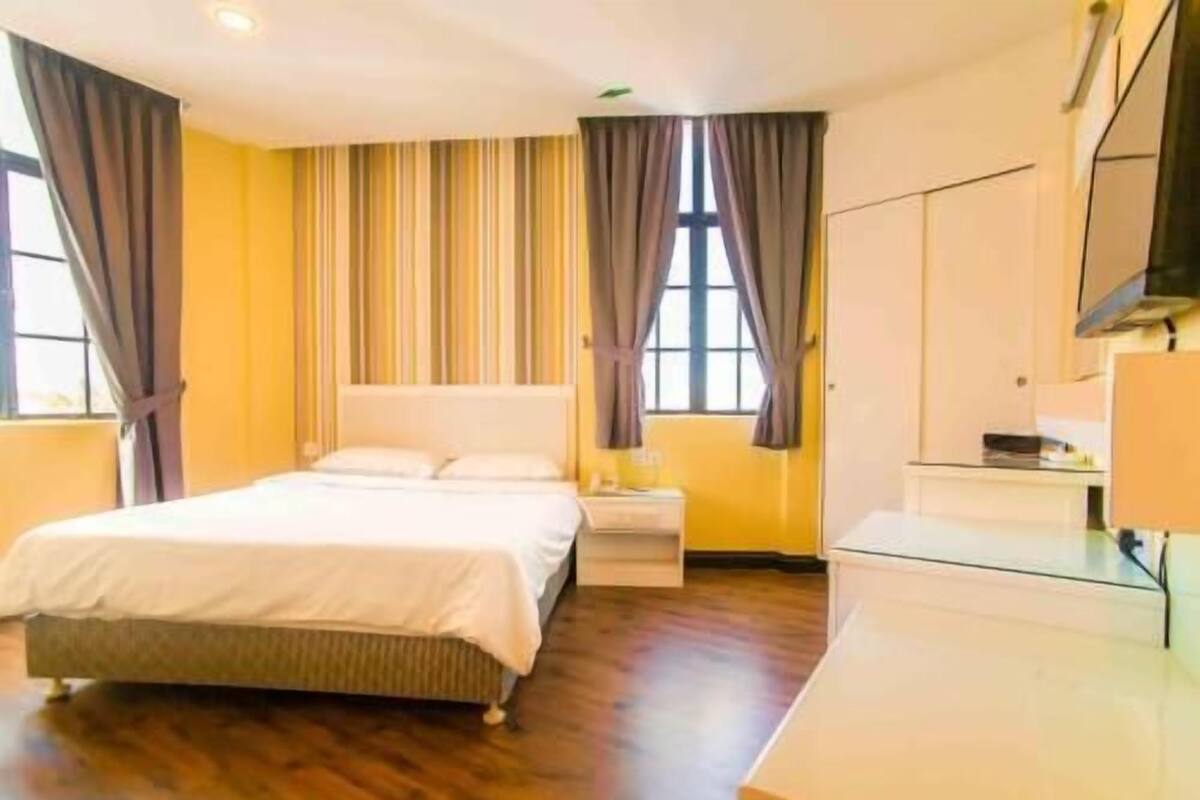A hotel room with a bed, bedside table, and a TV.